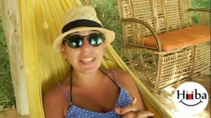 In this image, Hiba Najem is lying on a yellow hammock, wearing a hat and sunglasses